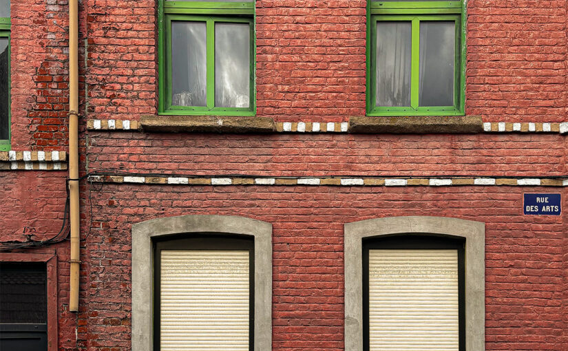 Old brick house façade with green woodwork sharply contrasting against the red brick. A 1930s house.